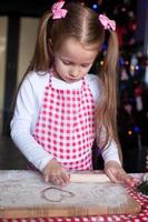 menina feliz com rolo assando biscoitos de gengibre para o natal foto