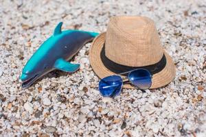 acessórios de verão, óculos de sol, brinquedos de praia e chapéu na praia branca foto