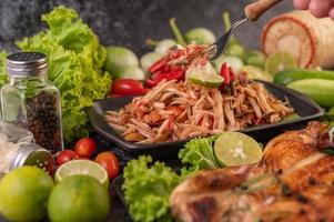 salada tailandesa de mamão rodeada de vegetais e frango