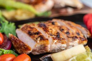 bife de frango com salada de legumes em um prato preto foto