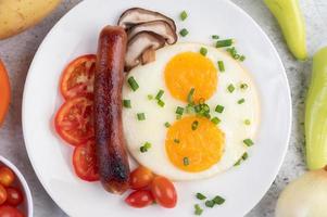 prato de café da manhã com ovos fritos, tomate, linguiça chinesa e cogumelos foto