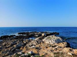 beira-mar rochosa com água azul foto