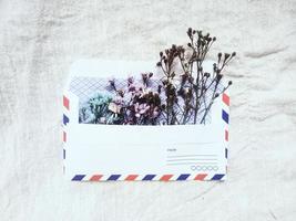 um envelope vintage com pequenas flores fofas. caixa de presente cartão para namorados em fundo de linho branco