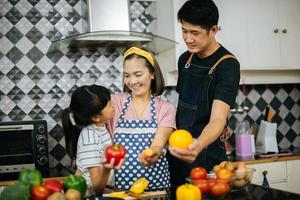 família feliz cortando vegetais juntos na cozinha foto