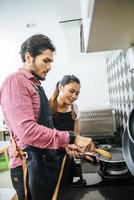 um jovem casal feliz cozinhando juntos em casa foto