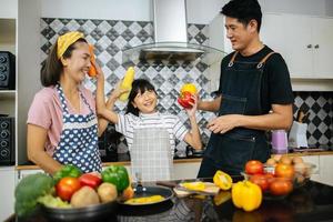 família feliz cortando vegetais juntos na cozinha foto