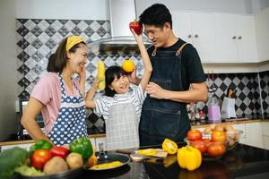 família feliz cortando vegetais juntos na cozinha foto