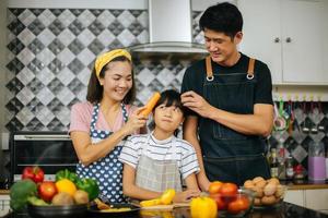 família feliz cortando vegetais juntos na cozinha foto