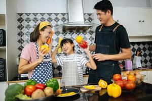 família feliz cortando vegetais juntos na cozinha foto