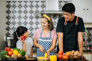 família feliz cortando vegetais juntos na cozinha foto