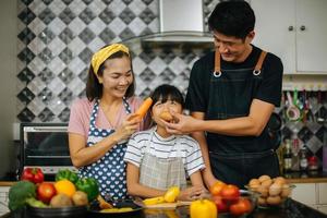 família feliz cortando vegetais juntos na cozinha foto