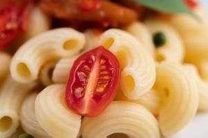 macarrão frito com tomate, pimenta, sementes de pimenta e manjericão foto