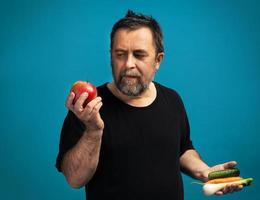 homem em uma camiseta preta segura frutas e legumes foto