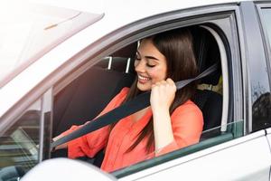 segurança primeiro. linda senhora caucasiana apertando o cinto de segurança do carro. bela jovem dirigindo seu carro novo. bela jovem dirigindo seu carro novo. cinto de segurança de fixação feminino no carro foto