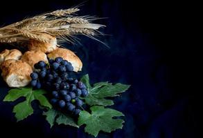 pão de uvas de trigo e coroa de espinhos em fundo preto como um símbolo do cristianismo foto