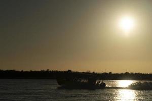 silhueta de barco a motor ao pôr do sol no oceano foto