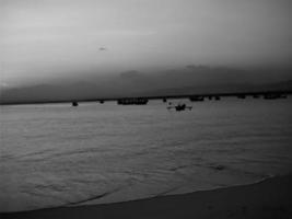 barco de pesca na praia ao pôr do sol. Preto e branco. foto