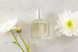 um frasco chique de perfume caro ou água de toalete em um fundo de mármore com flores brancas. vista do topo. uma maquete vazia da garrafa. anúncio. foto