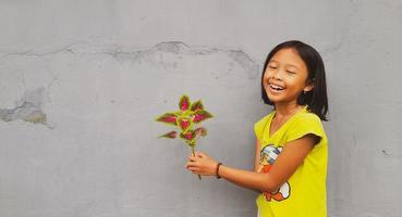 menina segurando planta jovem. folhas verdes. conceito de ecologia. fundo de cor clara. foto