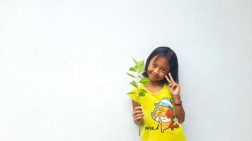 menina segurando planta jovem. folhas verdes. conceito de ecologia. fundo de cor clara. foto