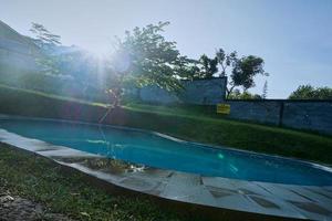 o ambiente na piscina do quintal pela manhã com raios de sol. foto