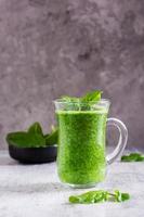 smoothie de espinafre fresco em um copo e uma tigela com folhas. antioxidante natural. visão vertical foto
