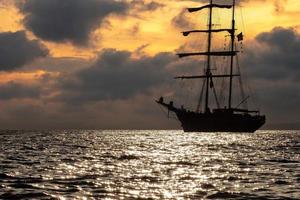 velha silhueta de navio ao pôr do sol foto