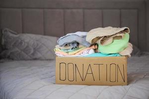 caixa de doação com roupas na cama. foto