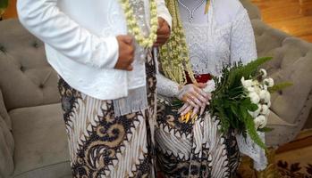 noivo e noiva em vestido de noiva branco segurando balde de flores foto