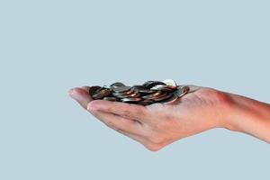 uma pilha de moedas na mão das pessoas isoladas em fundo azul. conceito de economia de dinheiro. foto