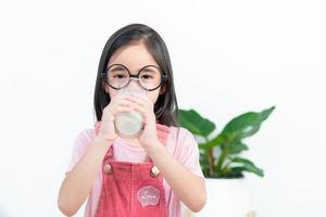 criança ásia menina beber leite com um copo foto