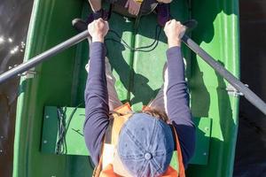 homem em um colete salva-vidas remando com remos em um barco e do outro lado do lago. conceito de estilo de vida ativo. vista do topo. foto