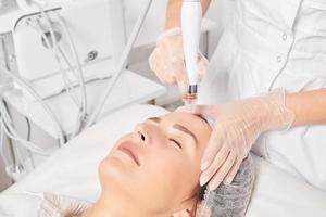 cosmetologista faz esfoliação aquática para rejuvenescimento cuidados com a pele do rosto feminino, procedimento no salão de beleza foto