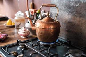 chaleira vintage de cobre no fogão a gás na cozinha moderna foto