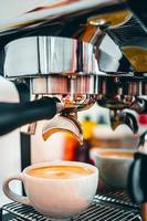 extração de café da máquina de café com um porta-filtro despejando café em uma xícara, café expresso saindo da máquina de café na cafeteria foto