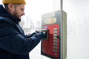 homem carrega a caixa do dispositivo com dinheiro em uma lavagem self-service em clima frio. foto