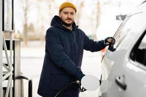 homem reabastecendo seu carro suv americano no posto de gasolina em tempo frio. foto