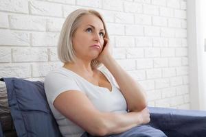 mulher triste sentada na cama de manhã. menopausa depressiva. foto