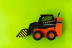 carregador de brinquedo laranja sobre fundo verde, mini carregador, carro industrial de brinquedo, carregador de rodas dianteiras de plástico foto