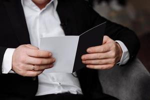 o noivo segura um envelope com uma carta da noiva. homem está lendo e sentado na cadeira perto da janela. uma carta para o noivo. declaração de amor. foto