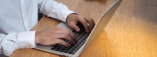 a mão humana usa o teclado do notebook na mesa. conceitos de educação e comunicação na internet foto