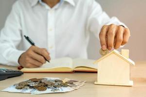 o homem está colocando duas moedas em suas economias a cada mês. um cofrinho de porco e é mostrado na frente como um símbolo de poupança. conceito de economia mensal. foto