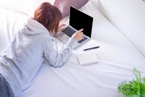 mulheres freelancers estudando ou trabalhando trabalhando no quarto em casa e conectando-se à internet via computador. trabalho de aprendizagem on-line de conceito de trabalho em casa. foto