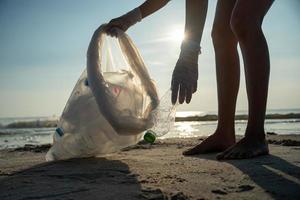 economize água. voluntário pegar lixo lixo na praia e garrafas de plástico são difíceis de decompor e evitar danos à vida aquática. terra, meio Ambiente, planeta verde, reduzir o aquecimento global, salvar o mundo foto