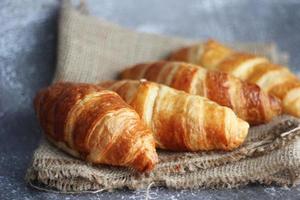 pão de croissant empilhado sobre a mesa com placas de madeira e pano de saco. foto