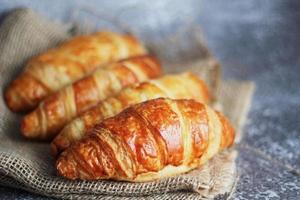 pão de croissant empilhado sobre a mesa com placas de madeira e pano de saco. foto