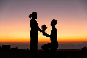 silhueta de casal de noivos apaixonados durante o nascer do sol com o fundo do céu da manhã. retratos pré-casamento imagens de casal feliz homem e mulher com céu natureza fundo. conceito de dia dos namorados. foto