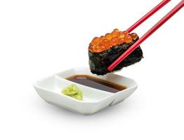 sushi enrolado de nigiri de ovas de salmão com pauzinhos vermelhos e molho de wasabi japonês isolado no fundo branco, inclui traçado de recorte foto