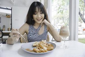engraçada jovem mulher asiática comendo macarrão saboroso no café foto
