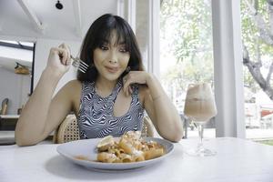 engraçada jovem mulher asiática comendo macarrão saboroso no café foto